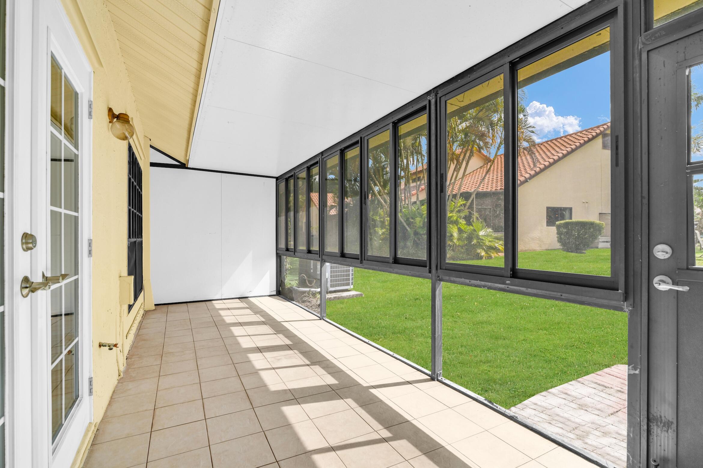 10296 Windswept Place Boca Raton, FL 33498 - Photo 23 of 64 a view of a porch with a floor to ceiling window chairs and floor to ceiling window
