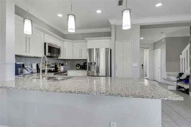 a kitchen with stainless steel appliances granite countertop a sink refrigerator and cabinets