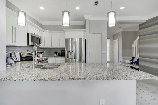 a kitchen with stainless steel appliances granite countertop a sink refrigerator and cabinets