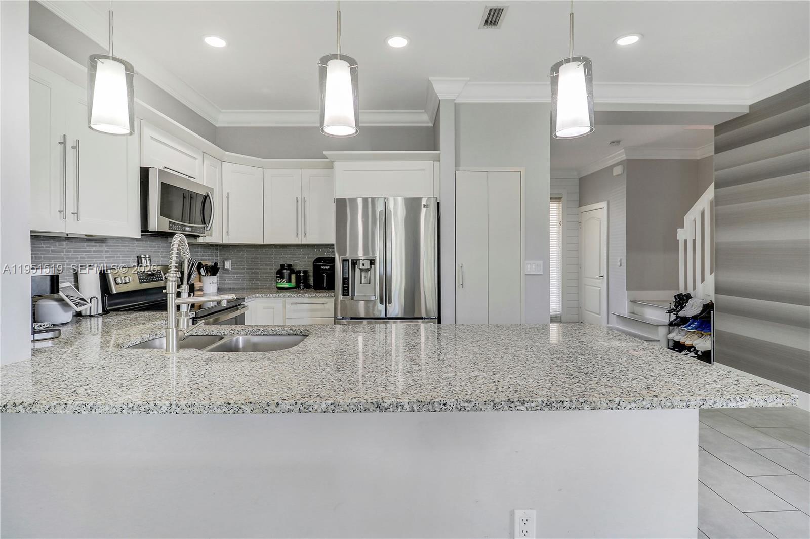 6047 Seminole Gardens Circle Riviera Beach, FL 33418 - Photo 14 of 40 a kitchen with stainless steel appliances granite countertop a sink refrigerator and cabinets