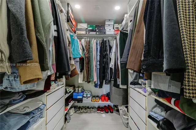 a view of walk in closet with clothes and shoes