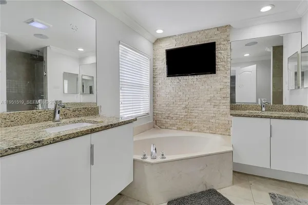 a bathroom with a granite countertop bathtub sink and mirror