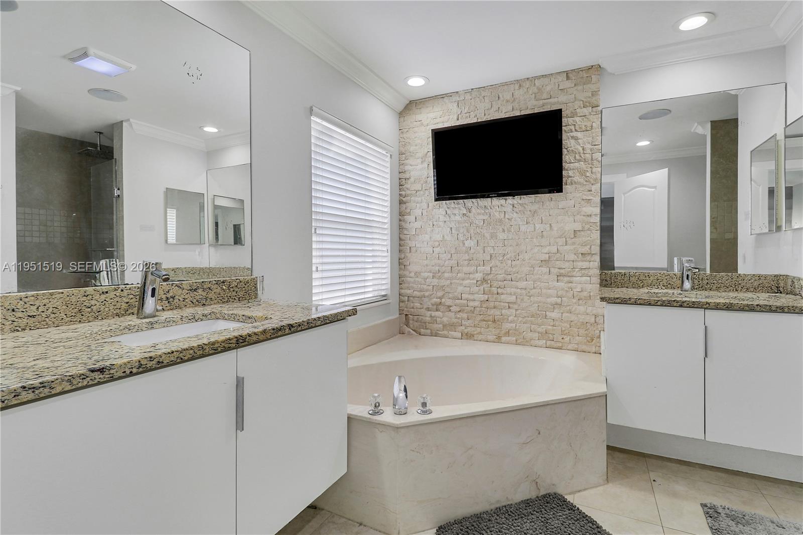 6047 Seminole Gardens Circle Riviera Beach, FL 33418 - Photo 25 of 40 a bathroom with a granite countertop bathtub sink and mirror