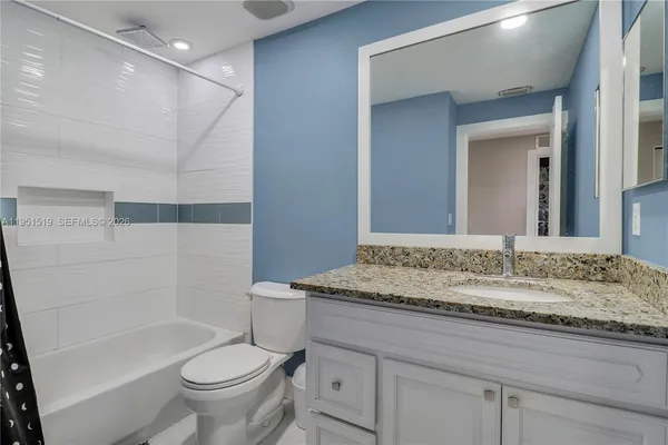 a bathroom with a granite countertop sink toilet and shower