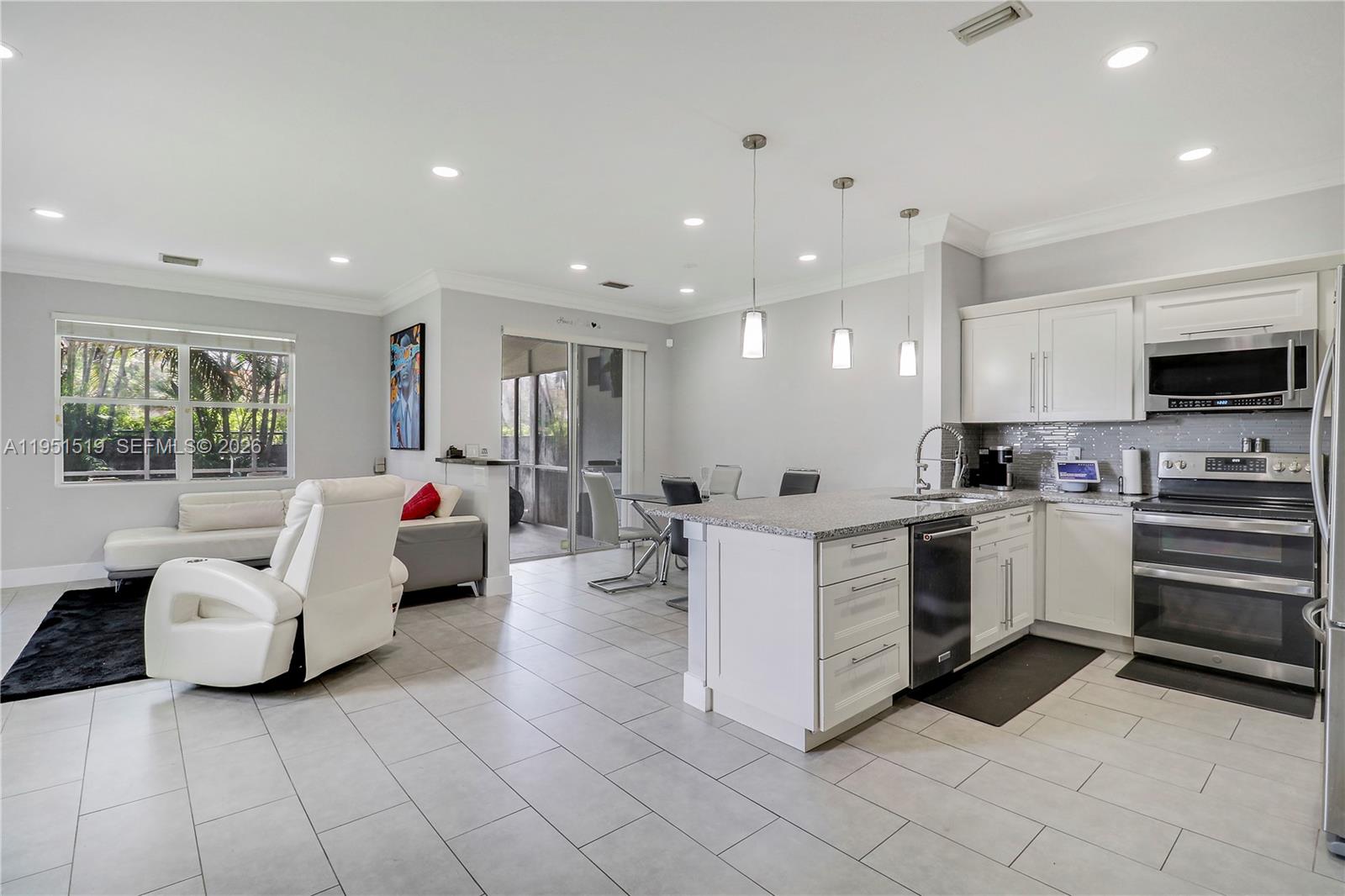6047 Seminole Gardens Circle Riviera Beach, FL 33418 - Photo 3 of 40 a large white living room with stainless steel appliances kitchen island granite countertop a refrigerator and a sink