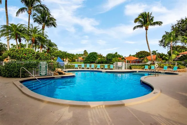 a view of a swimming pool with a lawn chairs under an umbrella