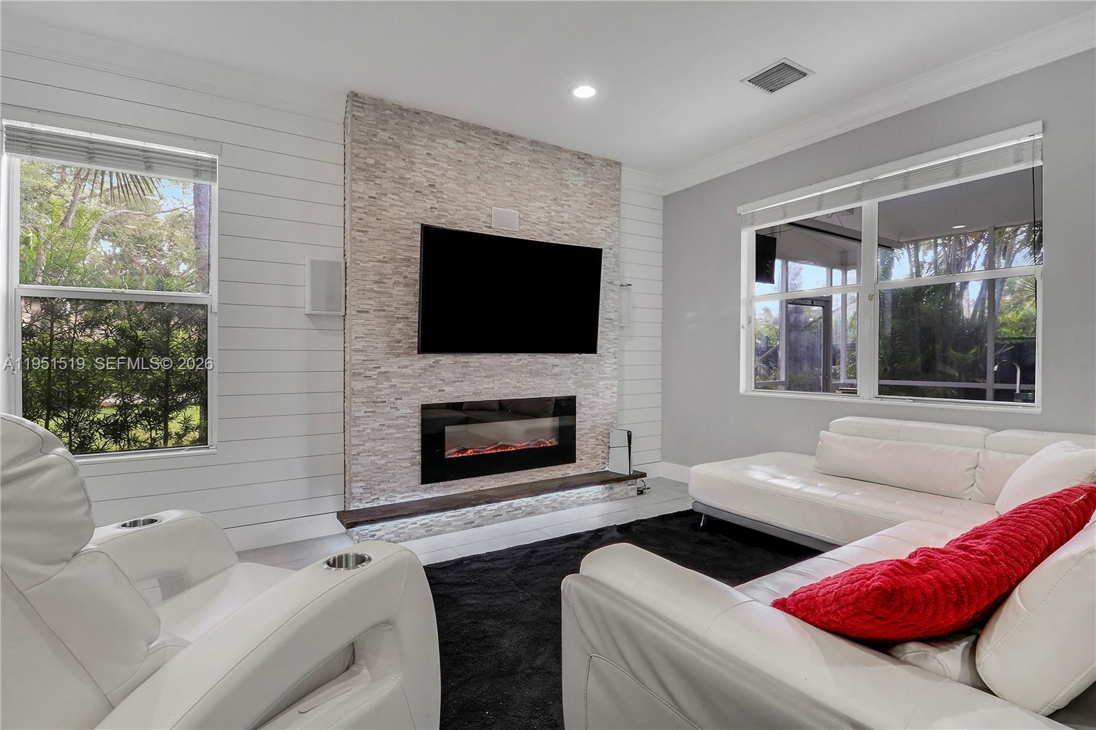 6047 Seminole Gardens Circle Riviera Beach, FL 33418 - Photo 6 of 40 a living room with furniture a flat screen tv and a fireplace