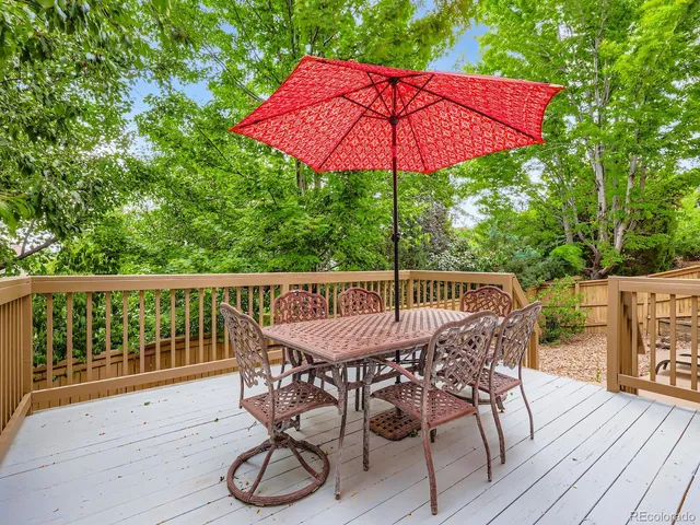 a patio with wooden floor a yard a table and chairs