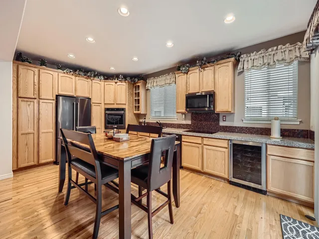 a kitchen with stainless steel appliances granite countertop a stove a refrigerator a microwave a sink dishwasher a dining table and chairs with wooden floor