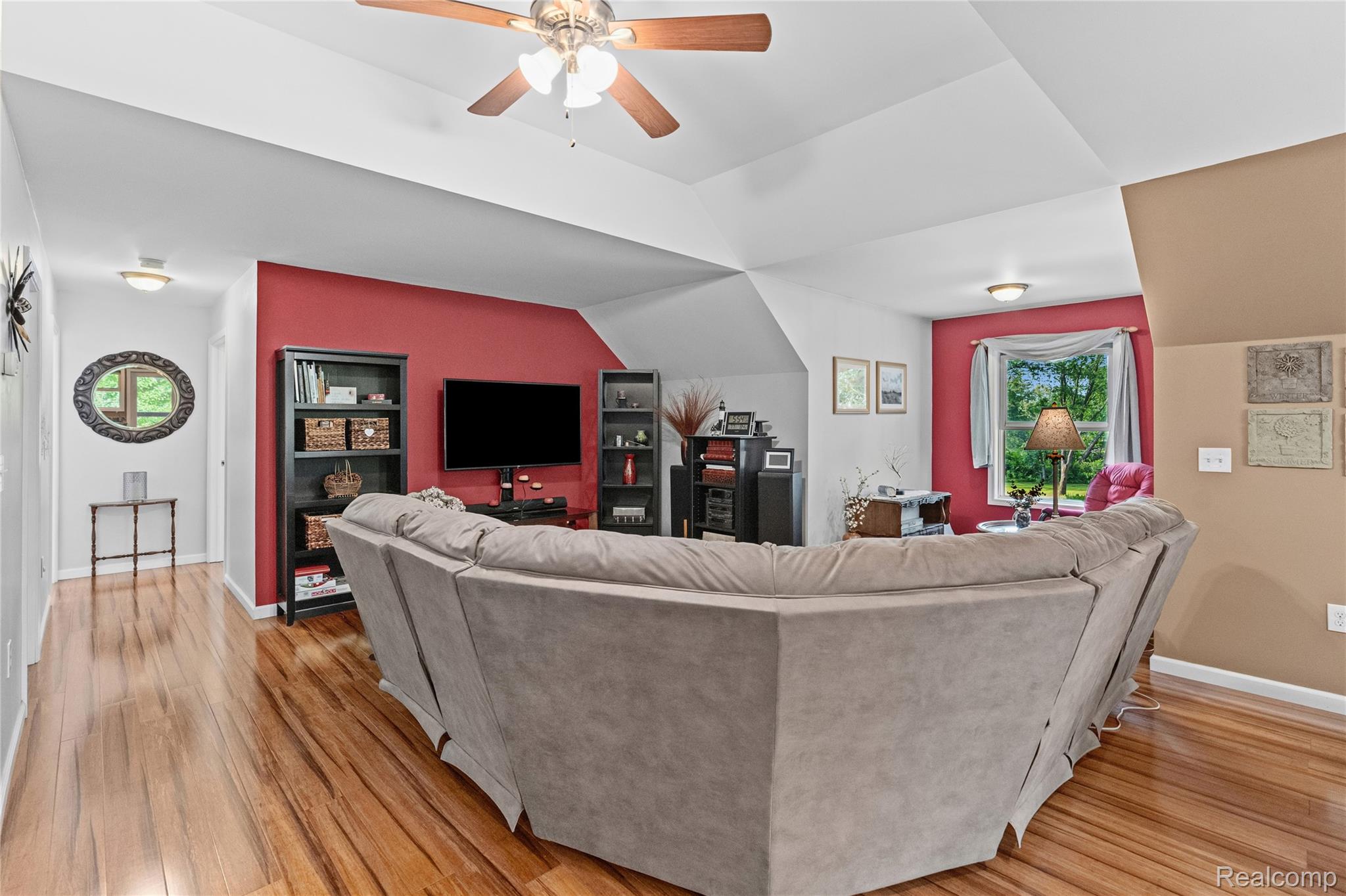 15055 South Duffield Road Byron, MI 48418 - Photo 11 of 61 Living area featuring wood-finish flooring, a tray ceiling with a ceiling fan, and a prominent accent wall