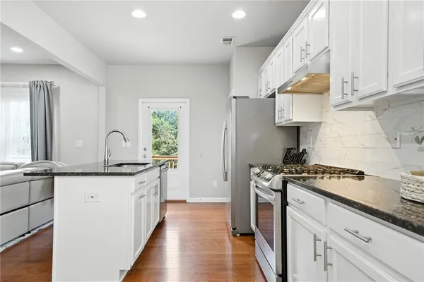 a kitchen with stainless steel appliances granite countertop a stove a sink and a white cabinets