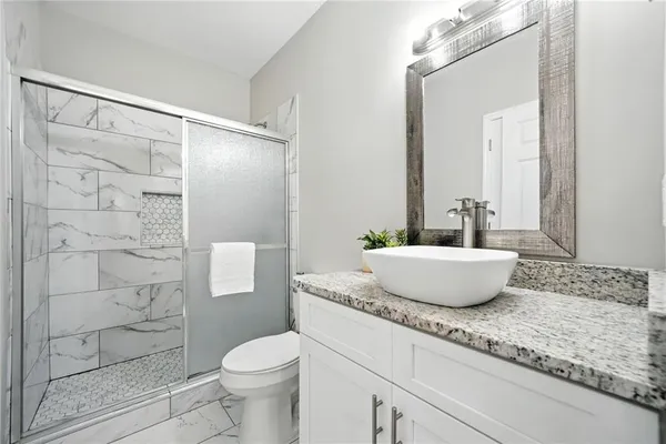 a bathroom with a granite countertop sink toilet and shower