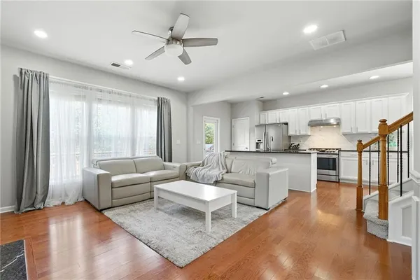 a living room with couches and kitchen view with wooden floor