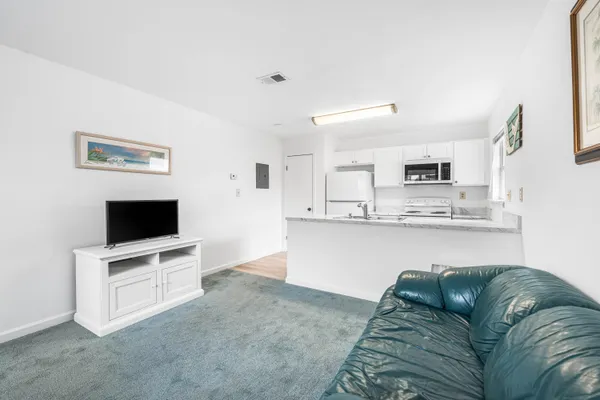 a living room with stainless steel appliances kitchen island granite countertop a couch and a flat screen tv