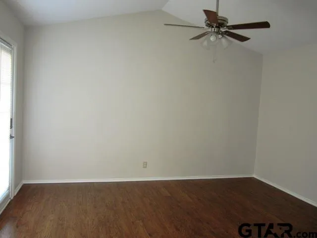 an empty room with wooden floor fan and windows