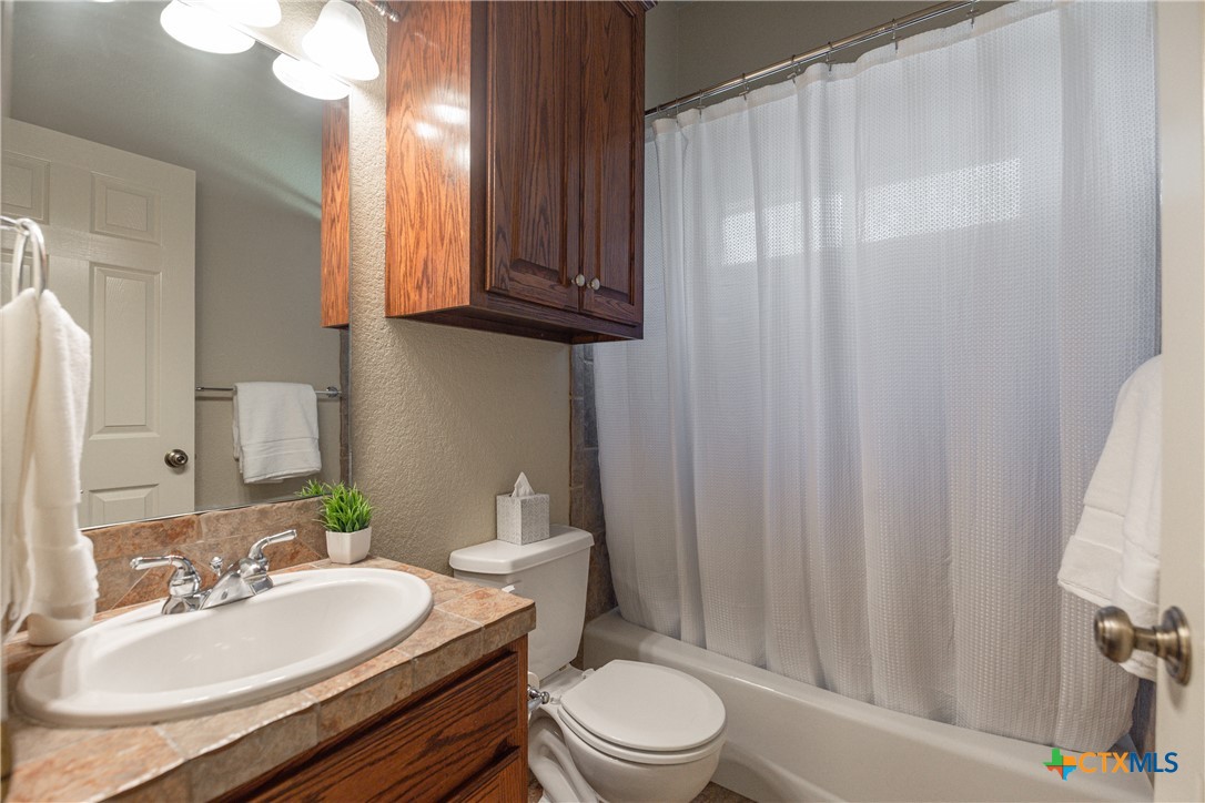 451 Winding View New Braunfels, TX 78132 - Photo 30 of 47 a bathroom with a sink a toilet and shower curtain