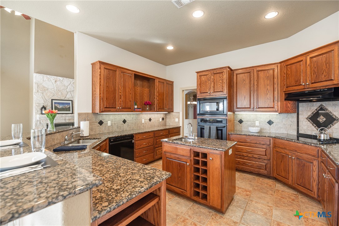 451 Winding View New Braunfels, TX 78132 - Photo 4 of 47 a kitchen with stainless steel appliances granite countertop a stove top oven a sink dishwasher and wooden cabinets with wooden floor