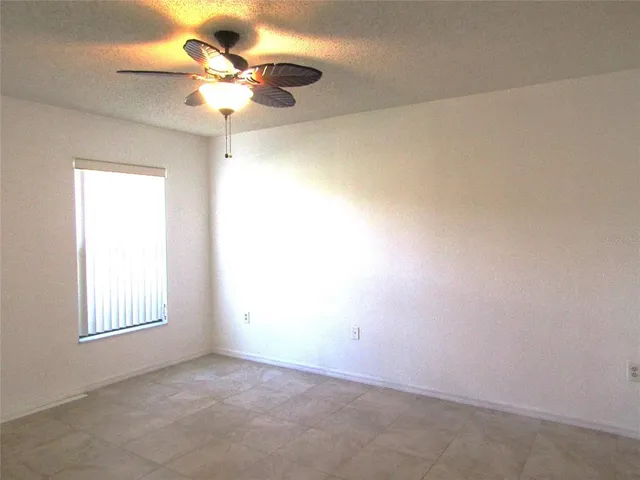 an empty room with a window and a ceiling fan