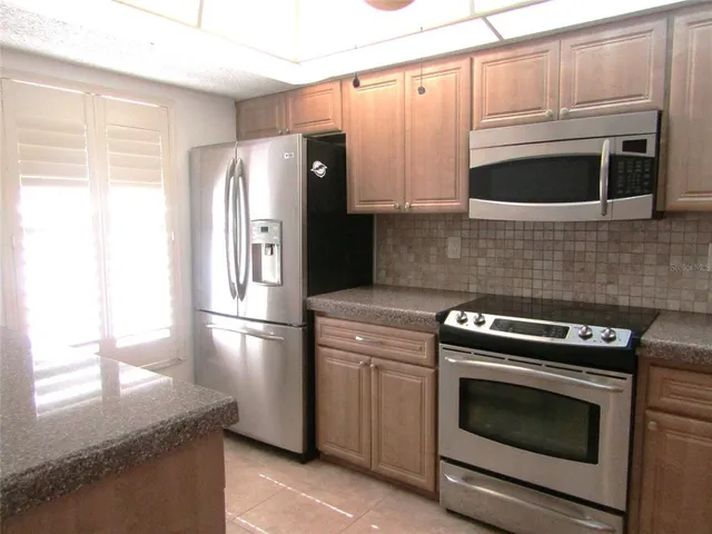 a kitchen with granite countertop white cabinets stainless steel appliances and window