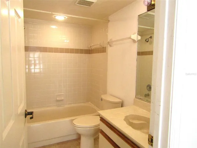 a bathroom with a granite countertop bathtub shower sink vanity and toilet