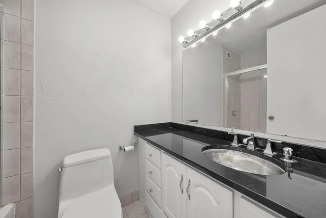 a bathroom with a granite countertop sink a toilet and a mirror