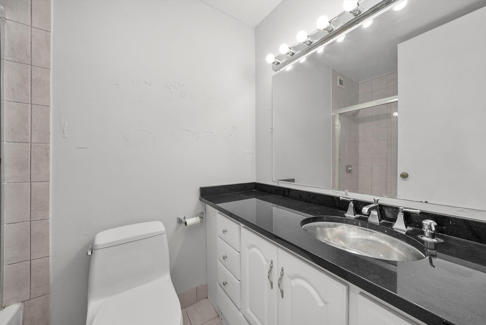1030 North State Street, Unit 39A Chicago, IL 60610 - Photo 15 of 36 a bathroom with a granite countertop sink a toilet and a mirror