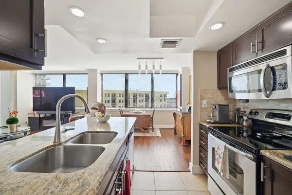 a kitchen with kitchen island a large counter top space a sink stainless steel appliances and cabinets