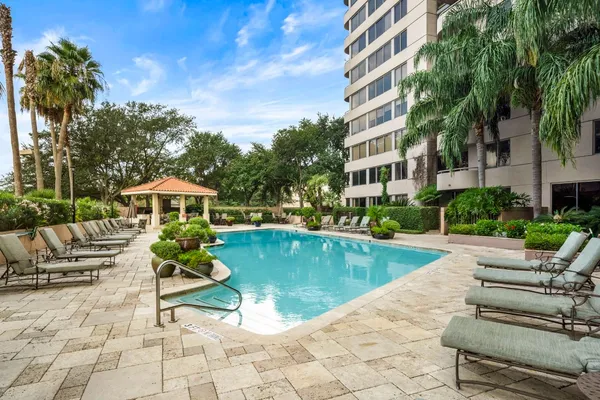 a view of a swimming pool with lawn chairs under an umbrella