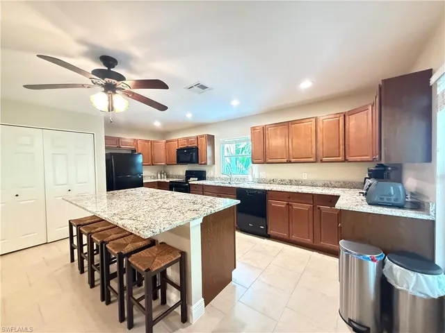 a kitchen with stainless steel appliances kitchen island granite countertop a table chairs sink and cabinets