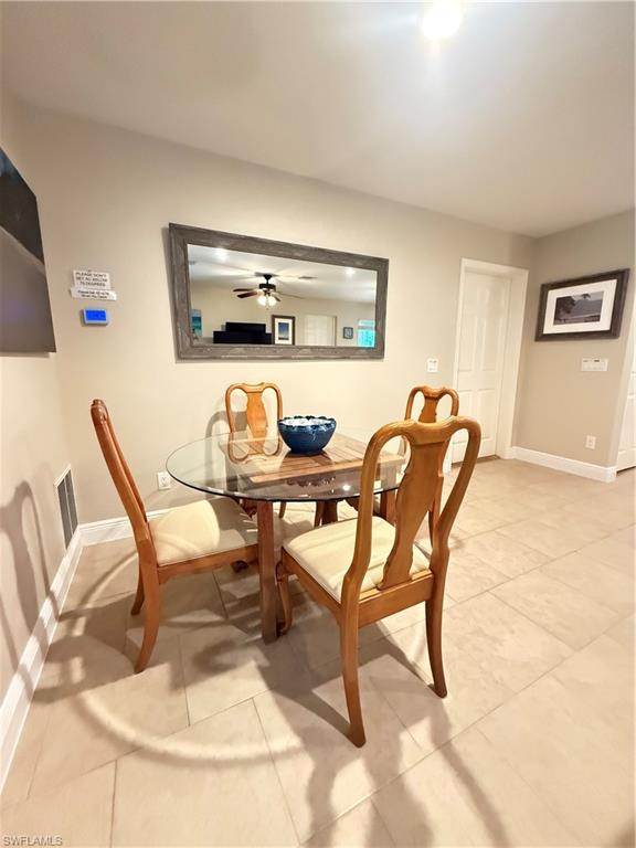 6140 Standing Oaks Lane Naples, FL 34119 - Photo 7 of 13 a dining room with furniture and a flat screen tv