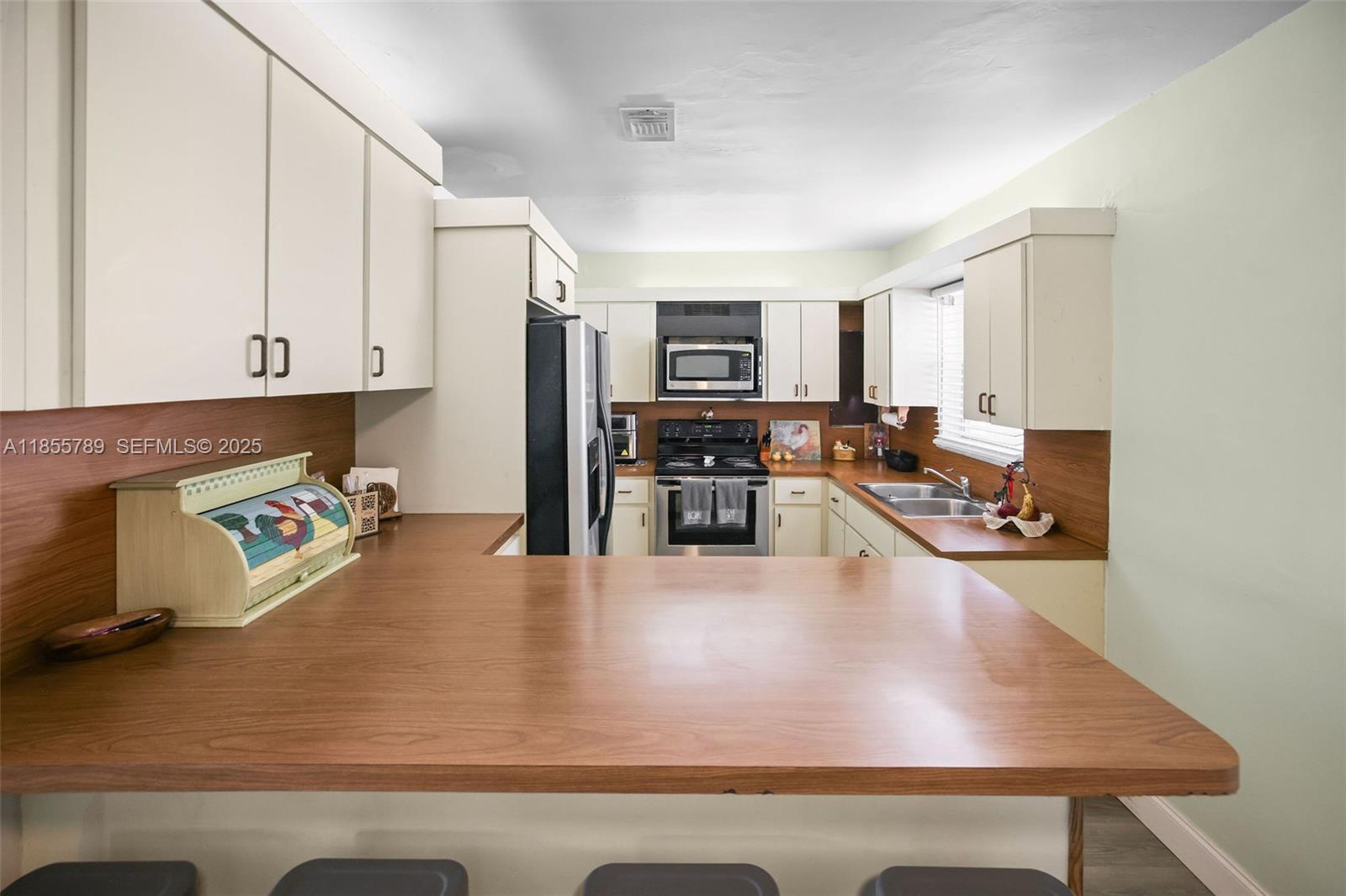 7550 Southwest 28th Street Road Miami, FL 33155 - Photo 7 of 27 a kitchen with stainless steel appliances granite countertop a stove top oven a sink a counter space and cabinets