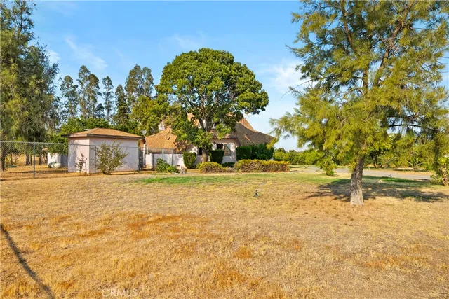 a backyard of a house with large trees and a barn