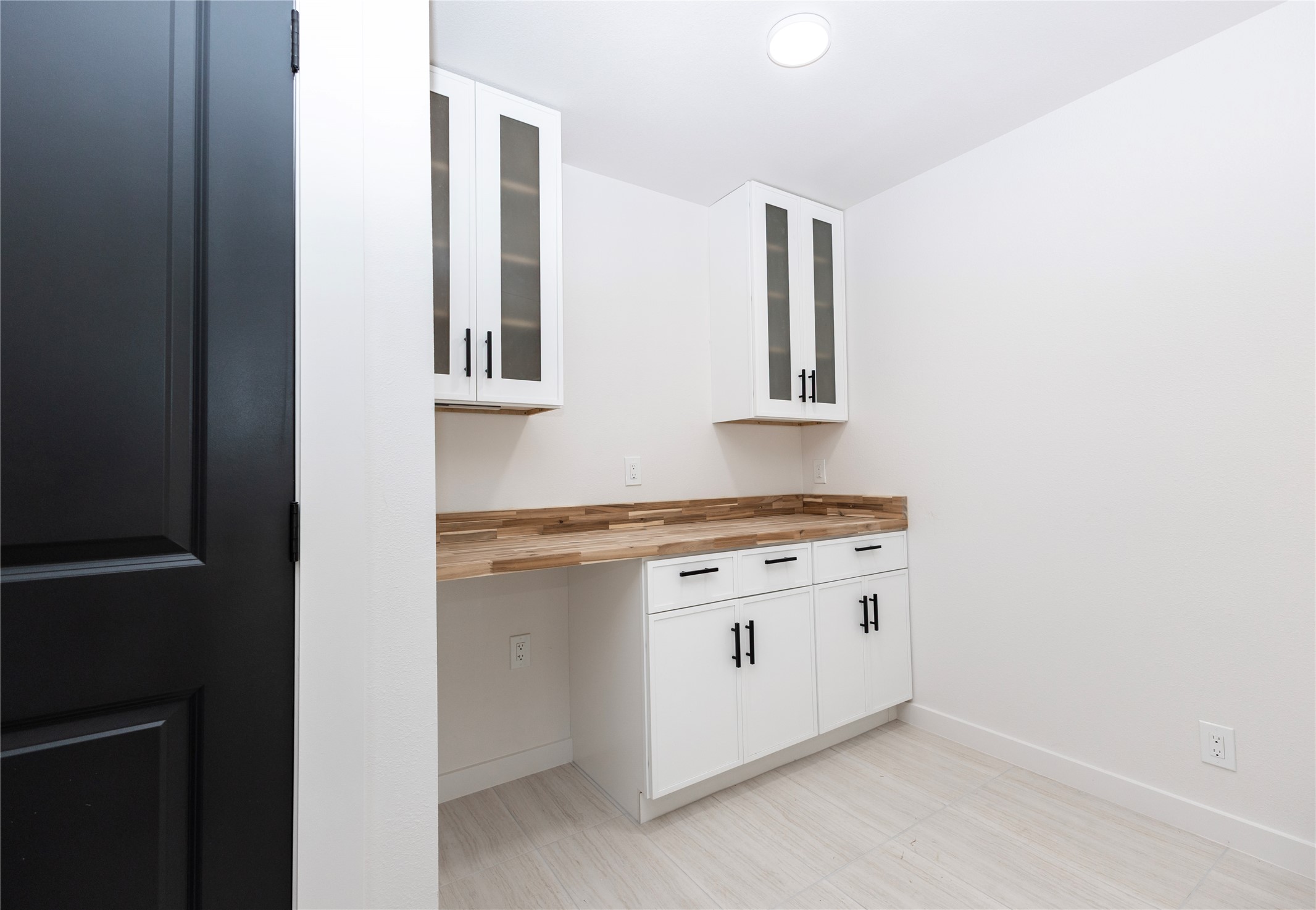 205 Bello Circle Georgetown, TX 78628 - Photo 13 of 36 A streamlined utility room offers generous storage with glass-front upper cabinets and a practical wood countertop.