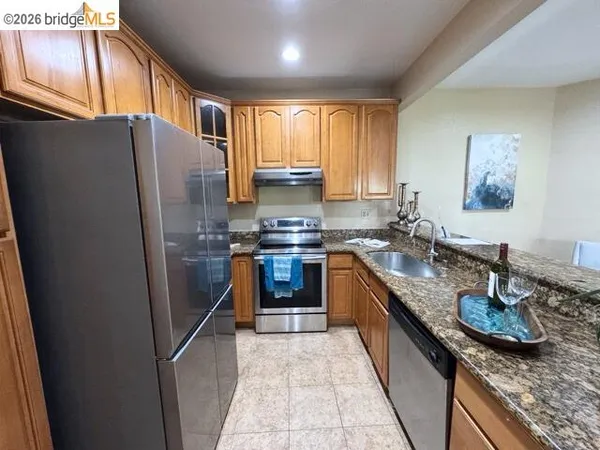 a kitchen with stainless steel appliances granite countertop a refrigerator a stove and a sink