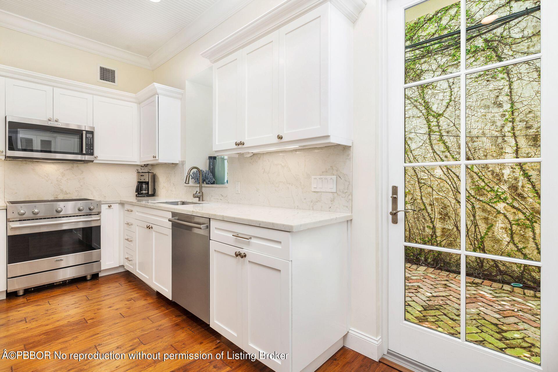 135 Root Trail, Unit A Palm Beach, FL 33480 - Photo 11 of 25 a kitchen with granite countertop white cabinets and white appliances