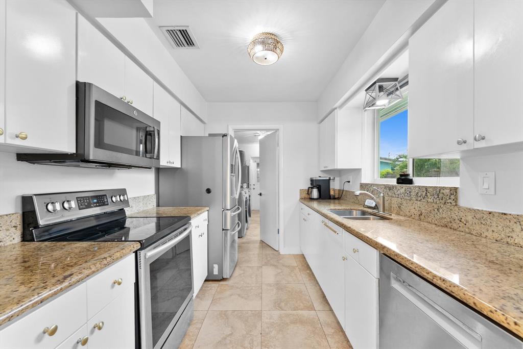 1257 Northwest 5th Street Boca Raton, FL 33486 - Photo 17 of 44 a kitchen with stainless steel appliances granite countertop a sink stove microwave and cabinets