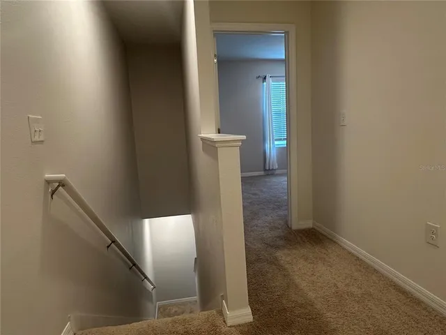 a view of a hallway with wooden floor and staircase