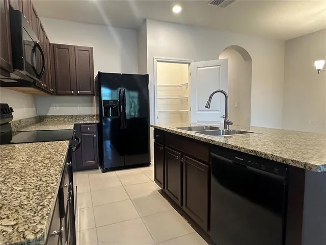 a kitchen with granite countertop a refrigerator and a sink