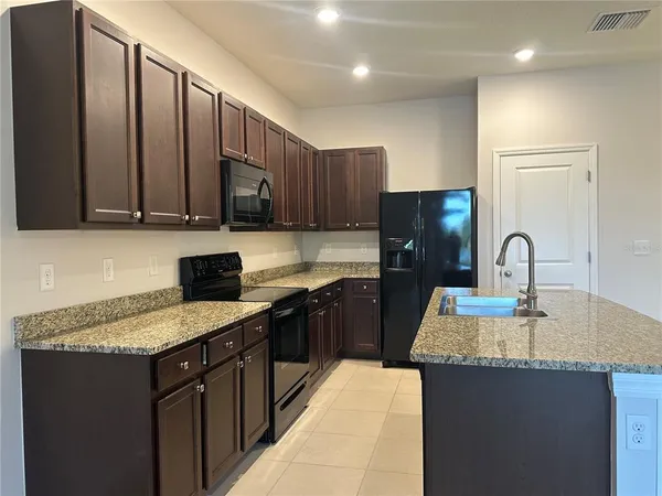 a kitchen with kitchen island granite countertop wooden cabinets granite counter tops and a stove