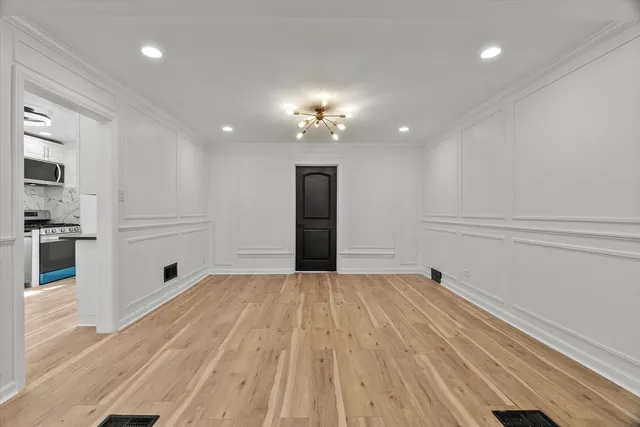 a view of an empty room with kitchen and a window
