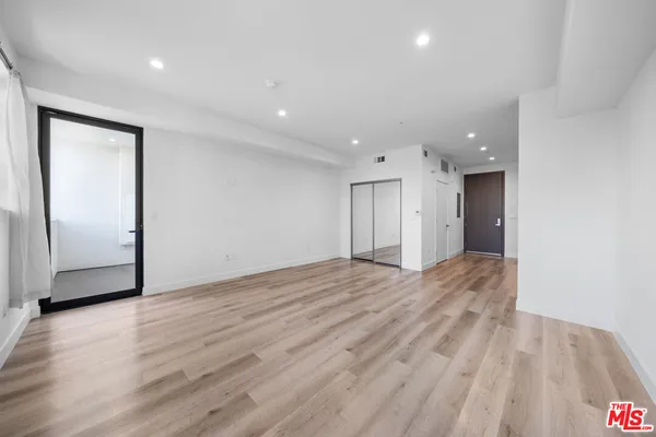 a view of an empty room with wooden floor and closet