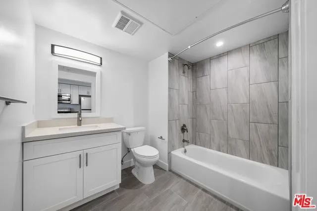 a bathroom with a toilet a sink a mirror a bathtub and vanity