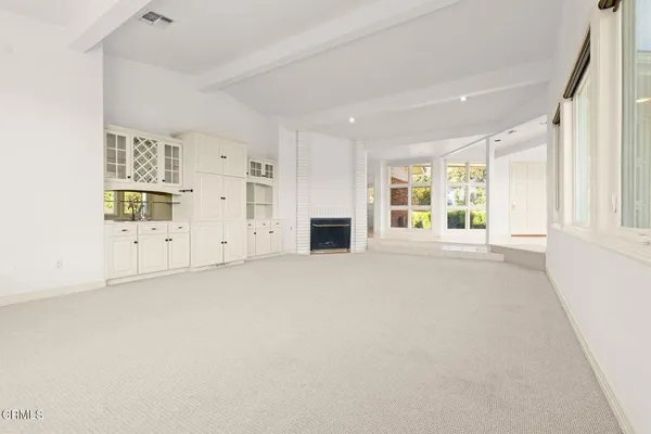 an empty room with wooden floor chandelier fan and windows
