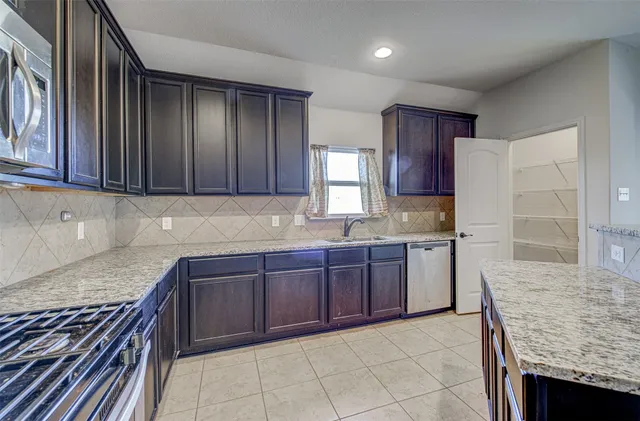 a kitchen with stainless steel appliances granite countertop wooden cabinets a stove top oven and granite counter top