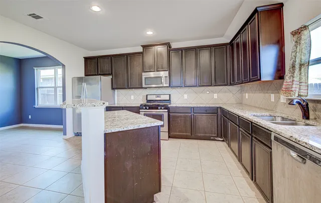 a kitchen with kitchen island granite countertop wooden cabinets a sink and a stove