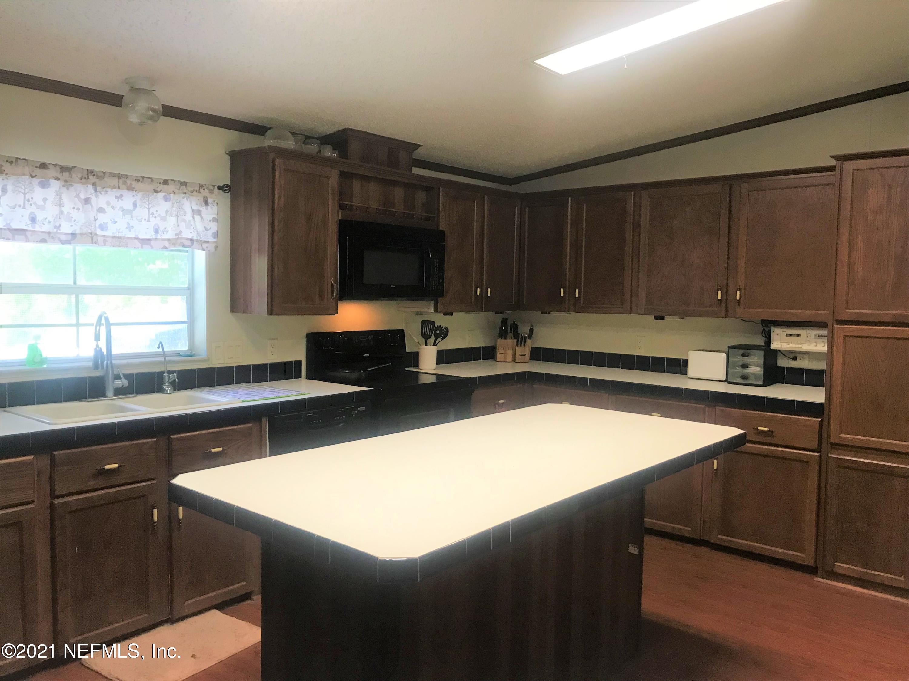 1860 Forbes Road St. Augustine, FL 32092 - Photo 3 of 24 a kitchen with a sink a stove a microwave and wooden cabinets