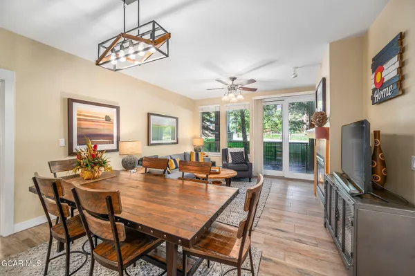 a dining room with wooden floor a chandelier a wooden table and chairs