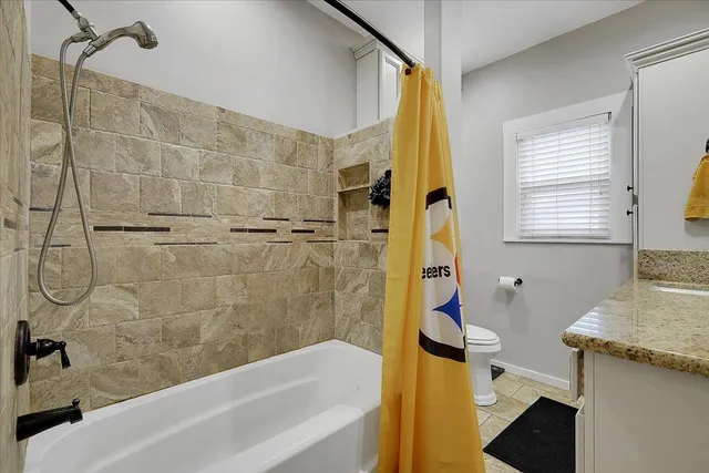 a bathroom with a granite countertop sink a toilet and shower