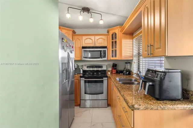 a kitchen with stainless steel appliances granite countertop a stove top oven a sink and a refrigerator