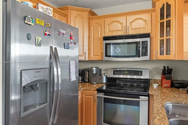 a kitchen with stainless steel appliances granite countertop a stove top oven a refrigerator and a microwave